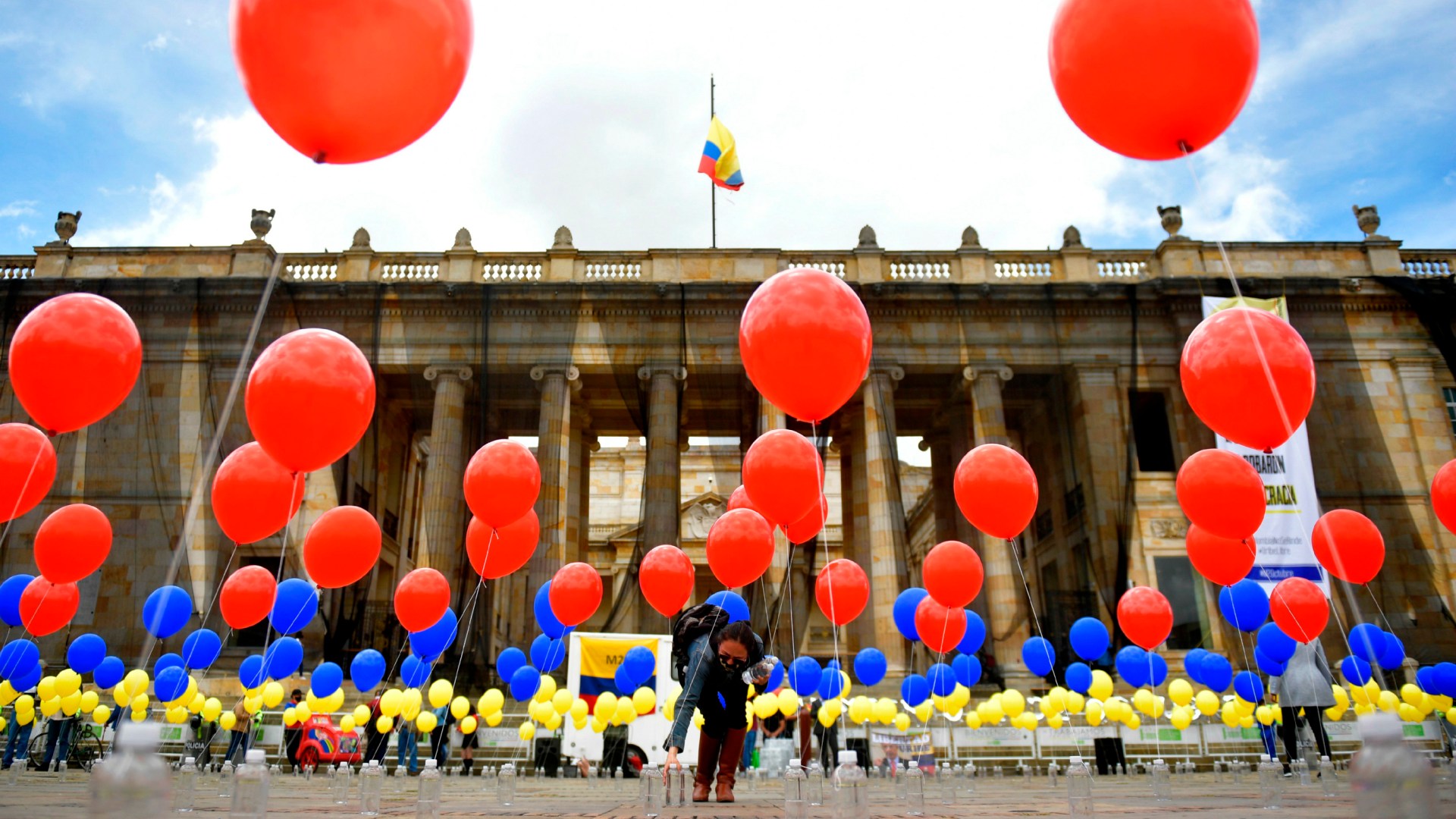 Una mujer coloca globos con los colores de la bandera nacional de Colombia en la Plaza Bolívar en Bogotá el 2 de octubre pasado, en conmemoración del cuarto aniversario del referendo para ratificar el histórico acuerdo de paz  entre el gobierno colombiano y los guerrilleros de las FARC, acuerdo que los votantes rechazaron por un margen estrecho.