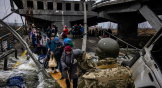 Ucranianos cruzan un puente destruido mientras huyen de la ciudad de Irpin, al noroeste de Kyiv [Kiev], el 7 de marzo de 2022.