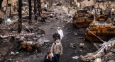 Personas caminando entre escombros y vehículos militares rusos en una calle en la ciudad de Bucha, Ucrania, el miércoles 6 de abril de 2022.