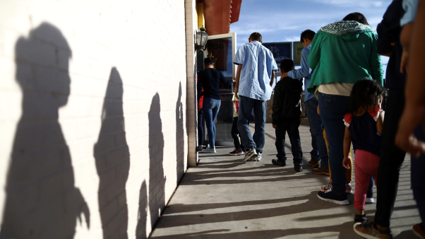 En El Paso, Texas, migrantes recién llegados desde Centroamérica hacen cola para recibir la cena en un refugio administrado por una iglesia.