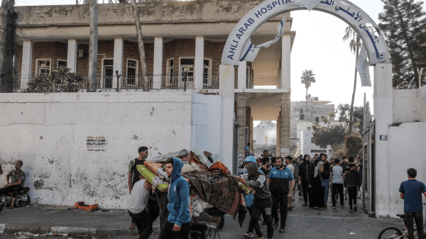 Palestinos rescatan objetos del edificio del Hospital Bautista al-Alhi en la ciudad de Gaza, gravemente dañado por un ataque de bomba el 18 de octubre de 2023.