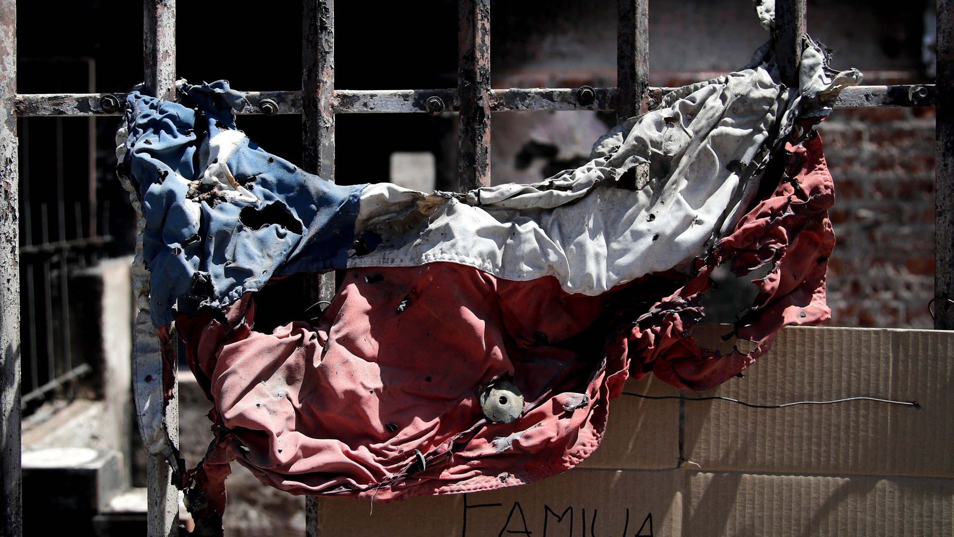 Los restos de una bandera chilena cuelgan de una casa consumida por las llamas durante los incendios forestales.