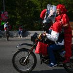 Una partidaria del gobierno viaja en la parte trasera de una motocicleta sosteniendo una imagen del presidente venezolano Nicolás Maduro.