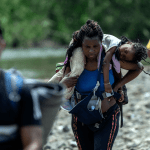 Una mujer migrante lleva a su hija en hombros cerca del primer control fronterizo de la provincia de Darién, en Panamá.
