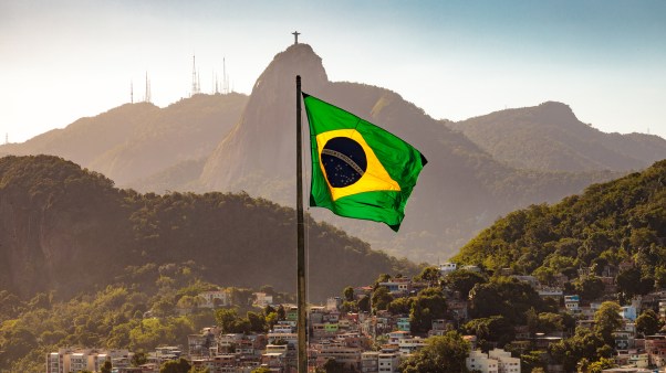 Brazil flag with the Christ the Redeemer statue on the mountain behind it