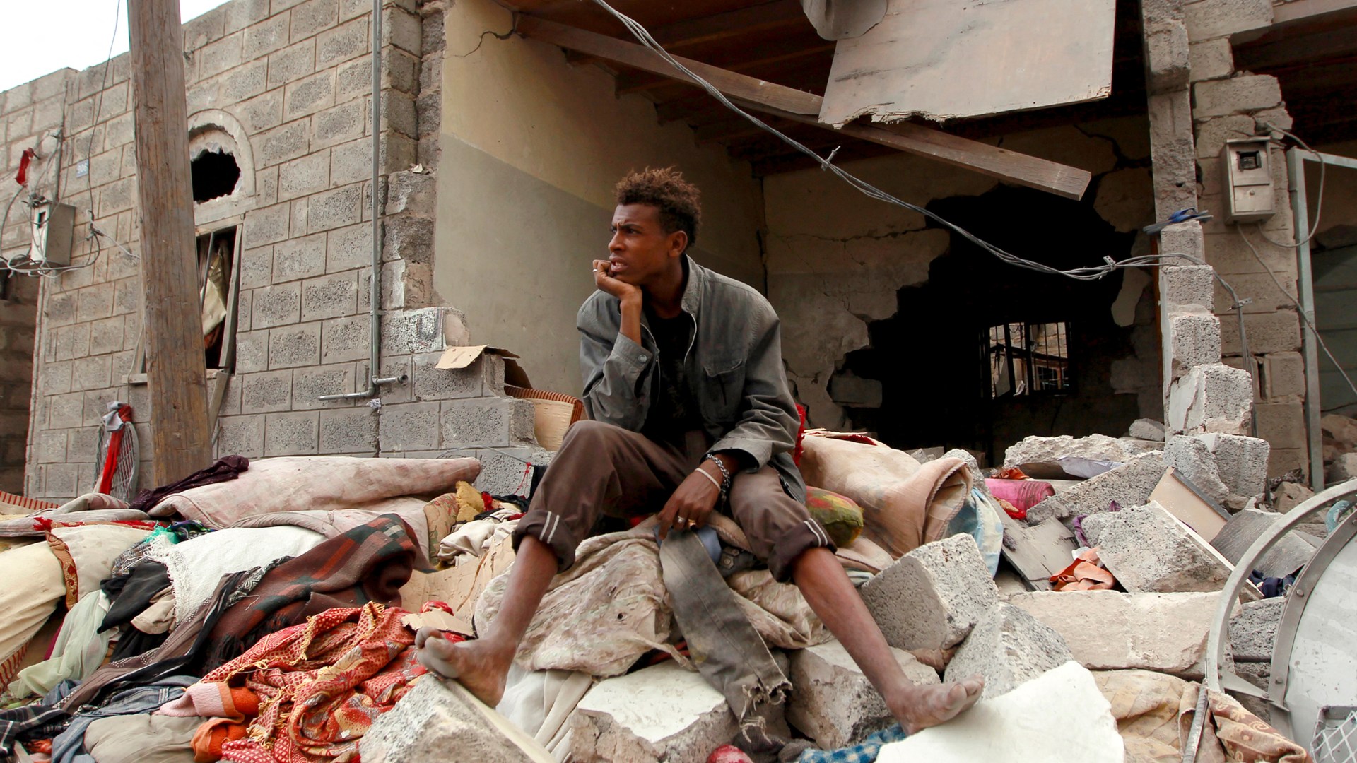 Un hombre yemení se sienta sobre los escombros de su casa dañada por un ataque aéreo.