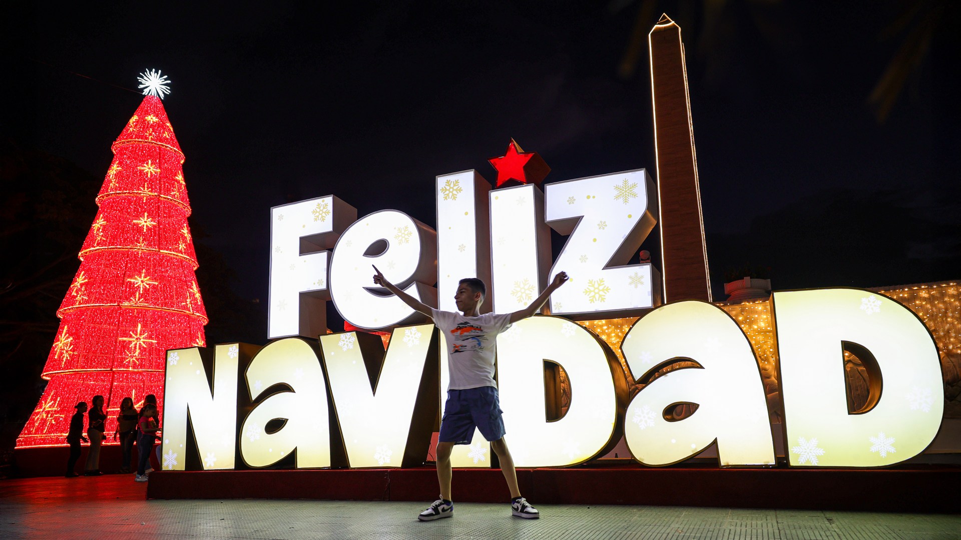 A child plays in front of a Merry Christmas sign as part of the Christmas celebrations in Venezuela