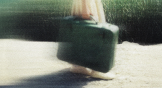 A blurry image of a woman carrying a suitcase.
