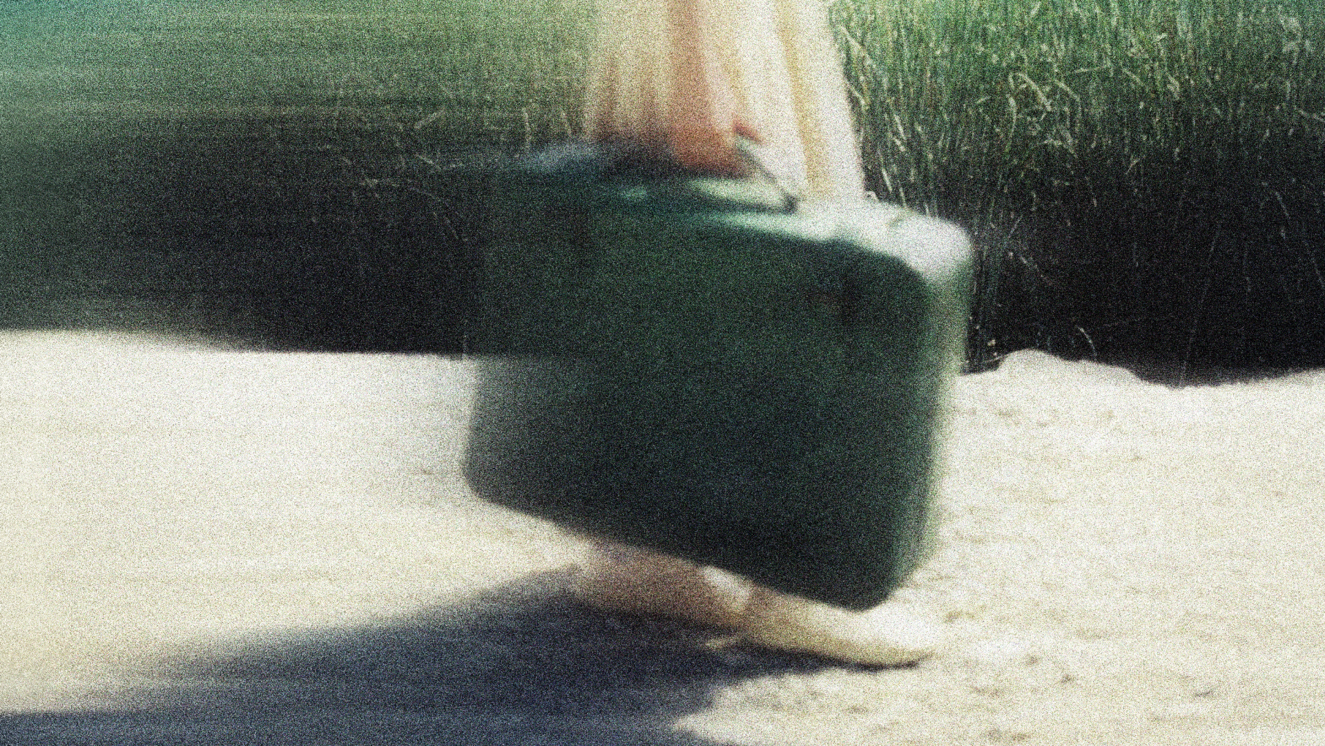 A blurry image of a woman carrying a suitcase.