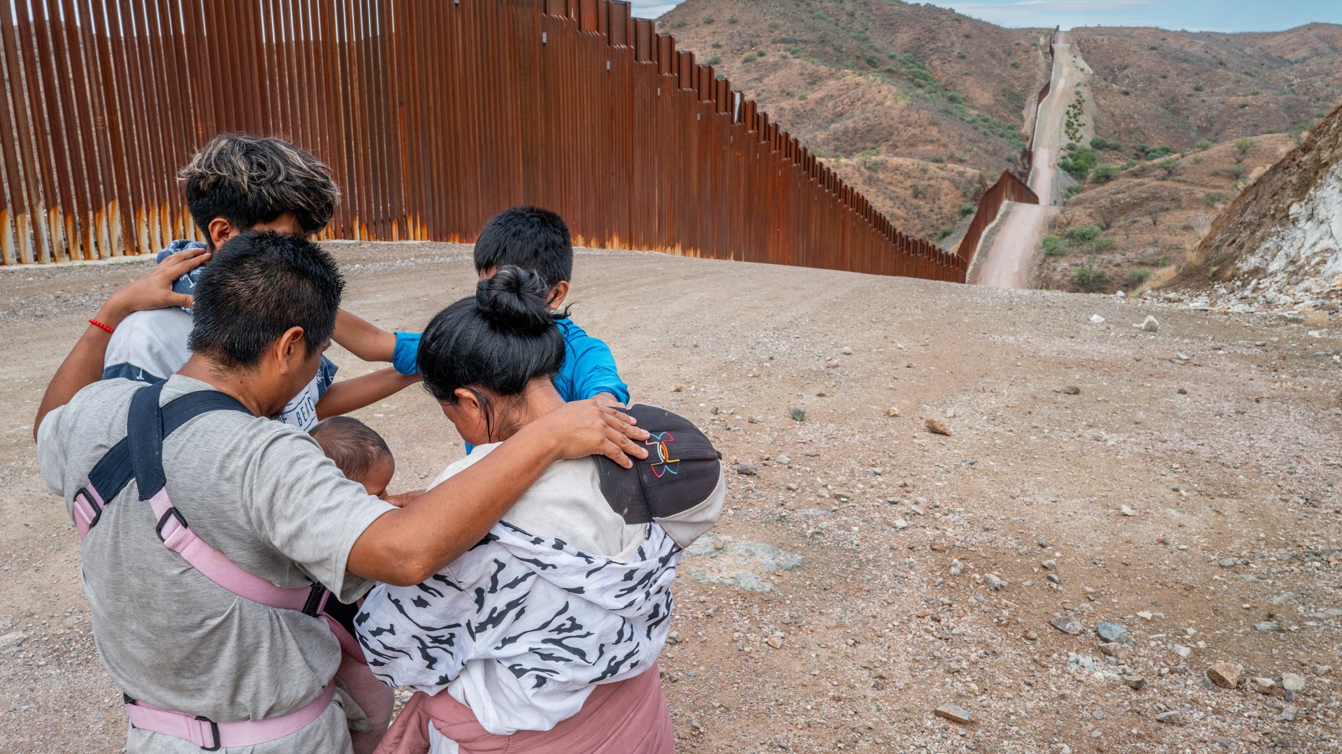 Una familia de inmigrantes ora en la frontera con Estados Unidos