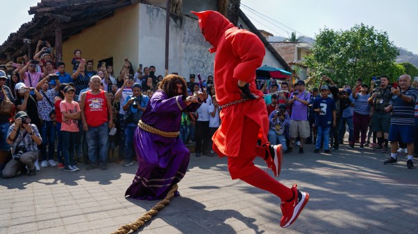 Salvadoreños vestidos de «talcigüín» y de Jesús, respectivamente, bailan durante la tradición de los Talcigüines en Texistepeque.