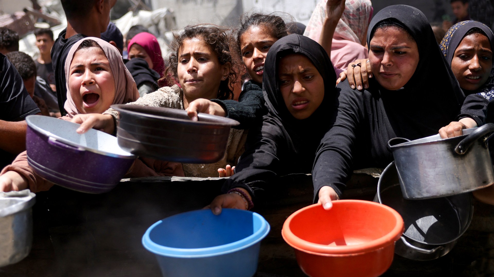Palestinos desplazados se reúnen para recoger raciones de comida en un punto de distribución de ayuda humanitaria en Gaza.