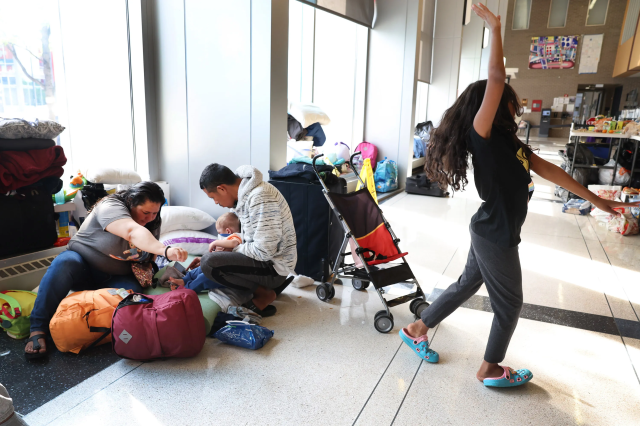 Migrantes de Venezuela esperan en el vestíbulo de una comisaría de Chicago tras llegar en autobús en mayo de 2023.