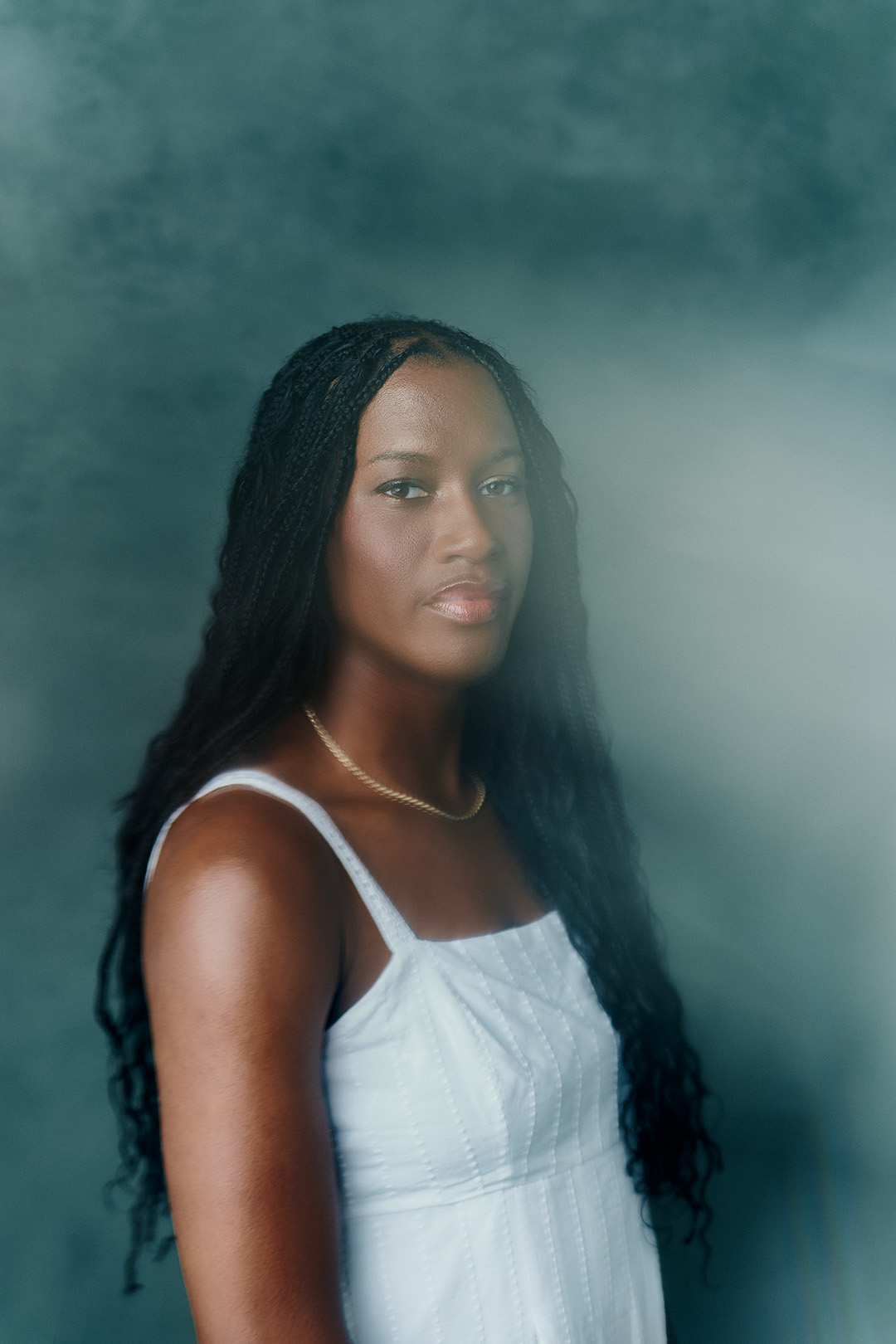 Headshot of Adira Polite on blue background with light obscuring her face