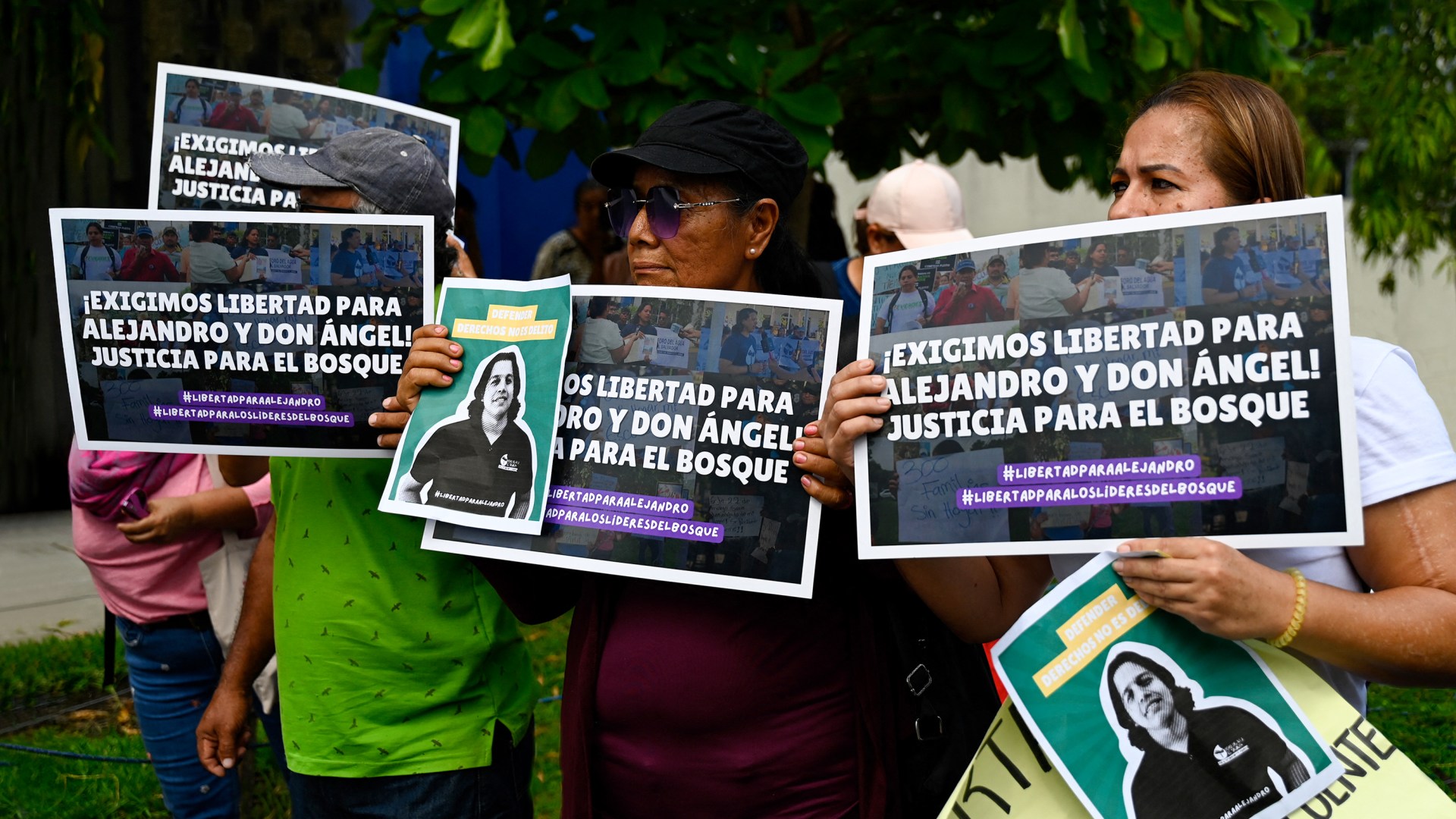 Un grupo de personas sostiene carteles para mostrar su apoyo al activista y abogado medioambiental salvadoreño Alejandro Henríquez y al pastor José Ángel Pérez, que han sido encarcelados.