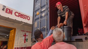 Miembros de la iglesia Hermanos en Cristo Faro de Luz descargando suministros que serán distribuidos a las personas de la iglesia y la comunidad.